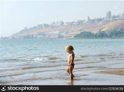 Child on the shore of lake Kinneret near the town of Tiberias in the summer in the morning