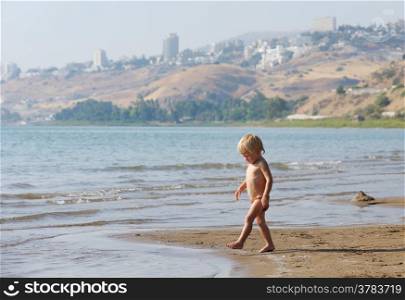 Child on the shore of lake Kinneret near the town of Tiberias in the summer in the morning