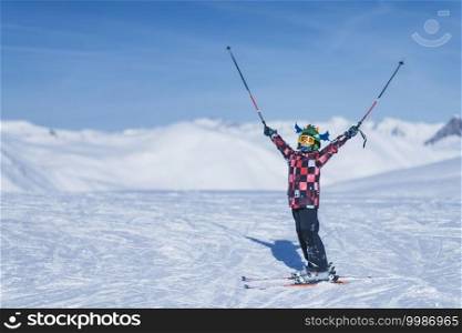 Child on top of ski resort enjoying with open arms. . Young Skier on Top of Ski Resort