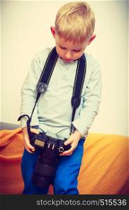 Child passion and hobbies concept. Kid playing with big professional digital camera, photographing various things in house. Kid playing with big professional digital camera