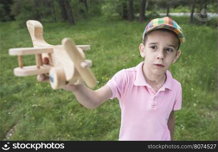 Child play with a wooden plane in the mountain. Forest