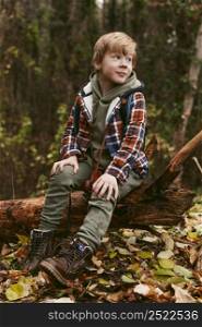 child posing nature while sitting tree trunk
