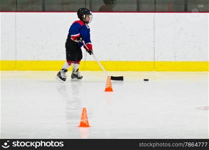 Child practices stickhandling at ice hockey practice