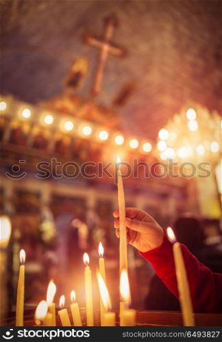 Child puts a candle in the church, praying with faith, traditional visit of a holy place for Easter, great Christian holiday, belief in God concept. Child puts a candle in the church