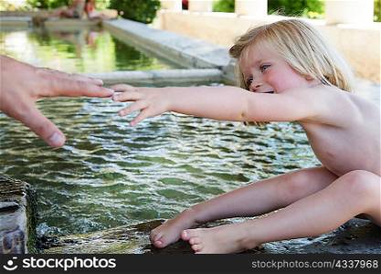 Child reaching for father?s hand in pool