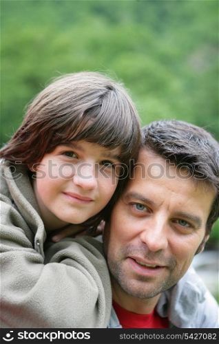 Child riding piggyback on his father&rsquo;s back