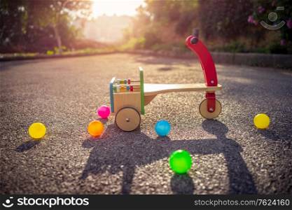 Child&rsquo;s bicycle on playground, vintage colorful wooden childish bicycle and colorful balls outdoors in sunny summer day