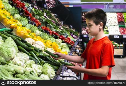 Child selecting vegetables on shelf in supermarket. Cabbage, zucchini, pepper and cauliflower.