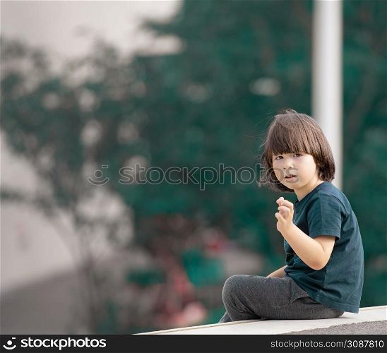 Child sits on the edge in the garden and looking back
