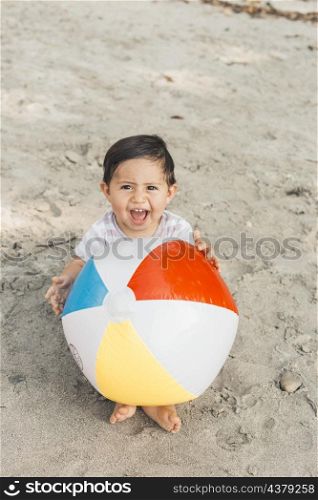 child sitting sand with inflatable ball