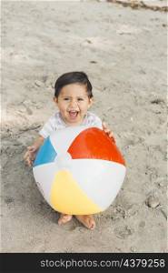 child sitting sand with inflatable ball