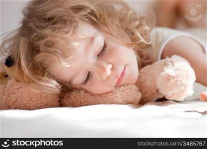 Child sleeping in bed with teddy