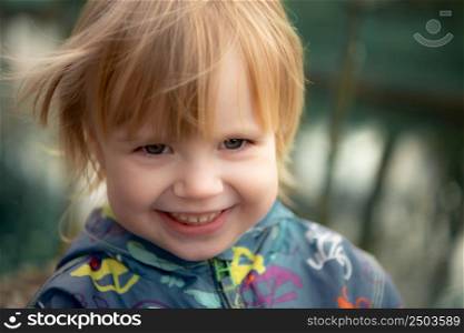 Child smiles face portrait on blurry background, outdoor