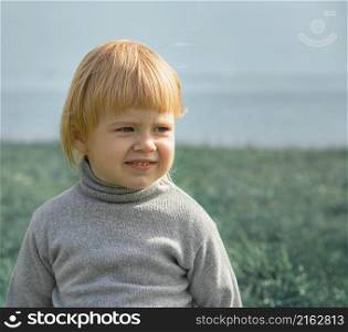 Child smiles face portrait on seashore background, outdoor