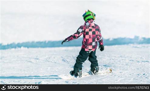 Child Snowboarding in the Mountains