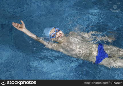 Child swimmer in swimming pool. Blue color swimming pool