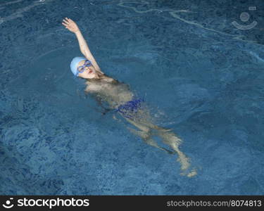 Child swimmer in swimming pool. Blue color swimming pool