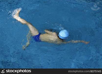 Child swimmer in swimming pool. Blue color swimming pool
