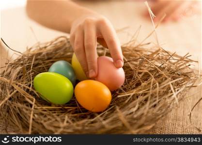 Child taking painted Easter eggs from the nest