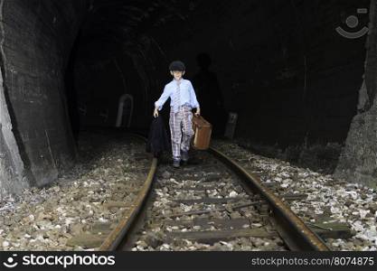 Child walking on railway road with vintage siutcase.