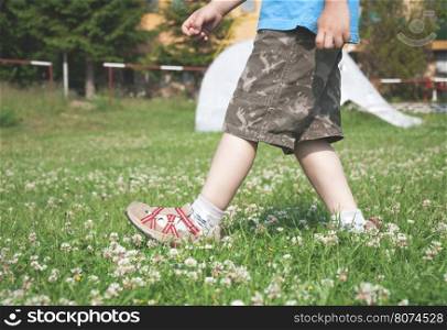 Child walking on the meadow with flowers