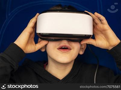 Child watching movie with VR glasses. Blue illuminated cabin with joysticks. Special effects. Technology and entertainment concept with virtual reality glasses.