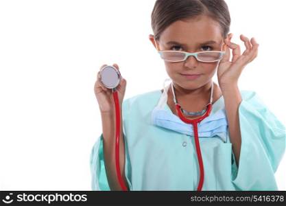 Child wearing grown up hospital scrubs, glasses and a stethoscope