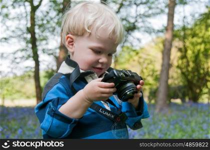 Child with a lumix camera, playing in a bluebell wood.