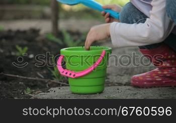 Child with a shovel and a bucket playing in the backyard