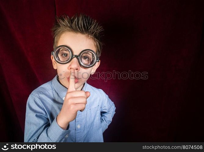 Child with big glasses. Red curtain background