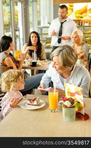 Child with grandmother at cafe eating cake sitting dessert restaurant