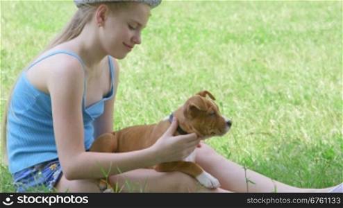 Child with puppy dog sitting on green lawn in summer day