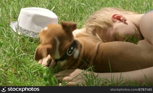 Child with puppy dreaming on grass in summer day