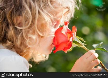 Child with rose flower in spring garden