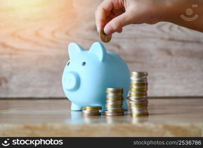 Child woman hand putting money coin into piggy bank for saving money for education study or investment , Stack coins Save money concept