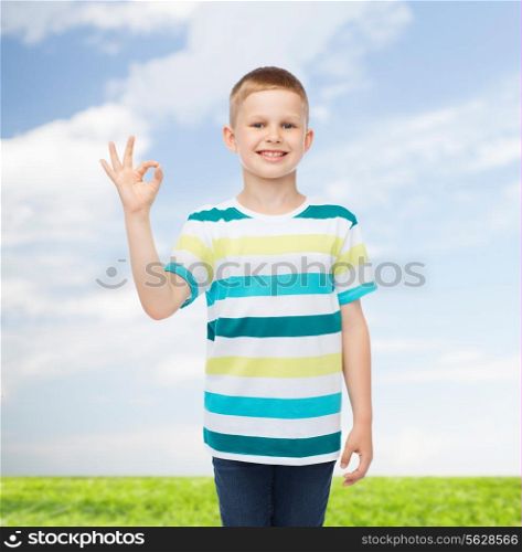 childhood, accomplishment, gesture and people concept - smiling little boy in casual clothes making OK gesture over natural background