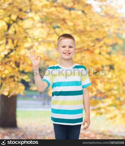 childhood, accomplishment, gesture and people concept - smiling little boy in casual clothes making OK gesture over autumn park background