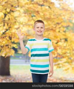 childhood, accomplishment, gesture and people concept - smiling little boy in casual clothes making OK gesture over autumn park background