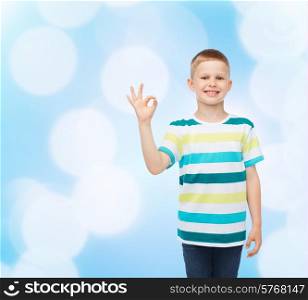 childhood, accomplishment, gesture and people concept - smiling little boy in casual clothes making OK gesture over blue background