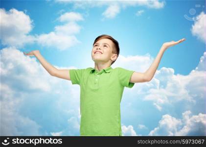 childhood, achievement, gladness and people concept - happy smiling boy in green polo t-shirt raising hands and looking up over blue sky and clouds background