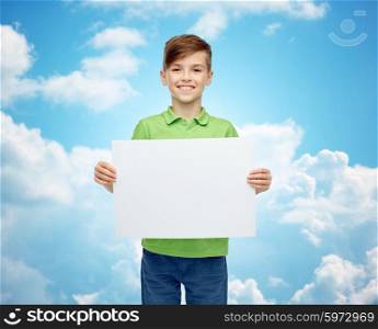 childhood, advertisement and people concept - happy smiling boy in green polo t-shirt holding white blank board over blue sky and clouds background