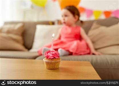 childhood and anniversary concept - birthday cupcake with one candle for baby girl at home party. birthday cupcake for baby girl at home party