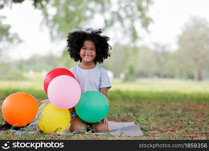 childhood and back emotion concept- little african american curly hair girl playing bolloons near sunflower field at outdoor.