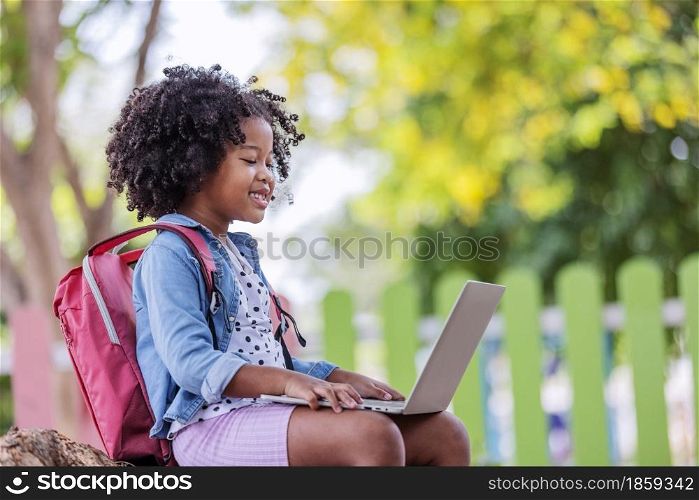 childhood and back new normal concept- little african american curly hair girl using laptop video call with friend after covid-19 pandemic lockdown.
