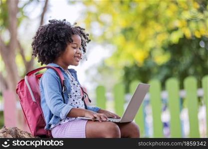 childhood and back new normal concept- little african american curly hair girl using laptop video call with friend after covid-19 pandemic lockdown.