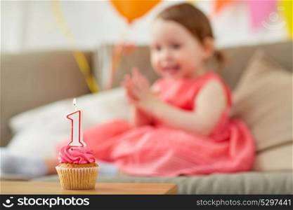 childhood and celebration concept - birthday cupcake with candle for baby girl one year anniversary at home party. birthday cupcake for child one year anniversary