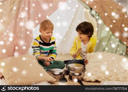 childhood and christmas concept - happy little boys with cooking pots playing music in kids tent at home over snow. boys with pots playing music in kids tent at home