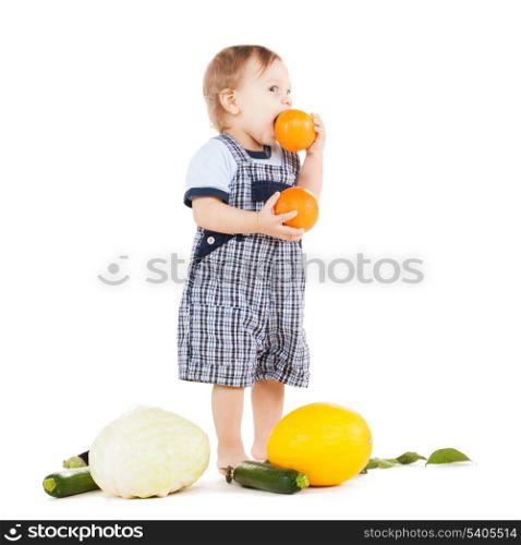 childhood and healthy food concept - cute toddler with vegetables eating orange