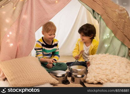childhood and hygge concept - happy little boys with cooking pots playing music in kids tent at home. boys with pots playing music in kids tent at home. boys with pots playing music in kids tent at home