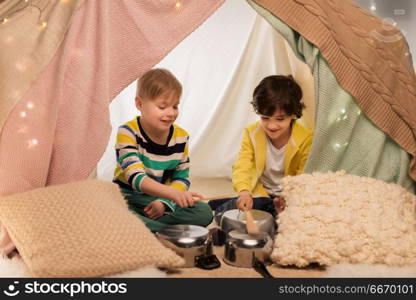 childhood and hygge concept - happy little boys with cooking pots playing music in kids tent at home. boys with pots playing music in kids tent at home. boys with pots playing music in kids tent at home